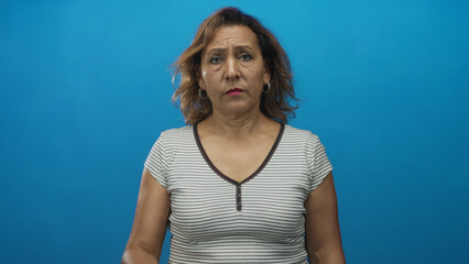 Woman with hand on forehead and closed eyes wearing striped top with hoop earrings in sharp blue studio light  fatigue. © Krakenimages.com