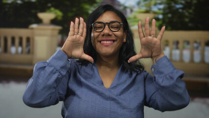 Woman framing with hand and glasses on sunlit bustling urban street in morning while smiling  creativity confidence. © Krakenimages.com