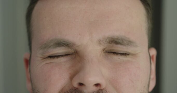 Close-up of a man with involuntary eye twitching. Concept of nervous tic, stress, fatigue and neurological or psychological tension.