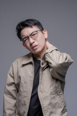 Obraz premium Asian man suffering from neck pain touching back of neck, muscle strain and stiffness concept, healthcare problem, tired male with glasses feeling discomfort, stress and office syndrome portrait isola