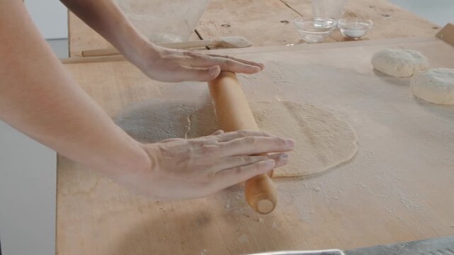 Chef kneading and rolling dough for baking