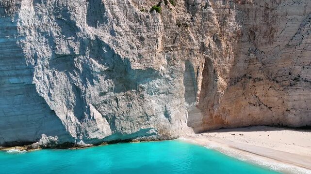 Aerial drone view of famous Navagio Shipwreck Beach with turquoise sea water and boats in Zakynthos island, Greece on a bright sunny da
