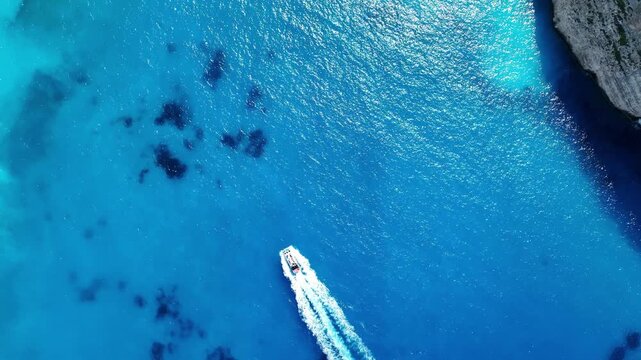 Aerial drone view of famous Navagio Shipwreck Beach with turquoise sea water and boats in Zakynthos island, Greece on a bright sunny da