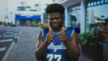 Fototapeta premium Man wearing blue basketball jersey gives thumbs up and points finger on street; approval encouragement.