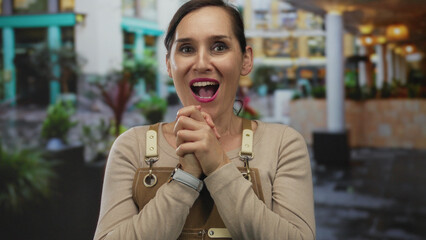 Woman wearing apron with surprised expression stands on city street surrounded by urban environment and plants, showcasing candid outdoor interaction in vibrant setting. © Krakenimages.com