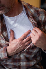 Man with heart problems, chest and abdominal pain at home measuring and checking pulse.