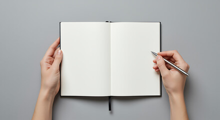 Obraz premium A person holding an open notebook and a pen over a gray background.