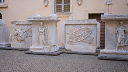 Historic marble reliefs and pedestal sculptures softly defocused in a sunlit courtyard museum background  background backdrop copyspace calm. © Krakenimages.com