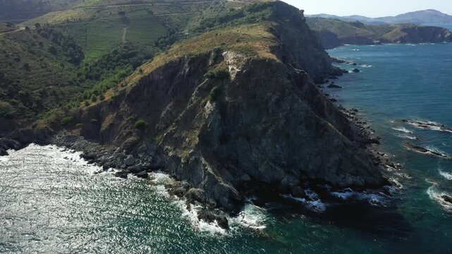 Aerial view of a rugged, rocky coastline with steep cliffs and turquoise sea near Banyuls sur Mer in southern France. Natural landscape with dramatic coastal scenery and Mediterranean vegetation.