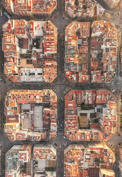 Aerial view of a grid of terracotta rooftops and sun-kissed facades form an intricate urban tapestry, showcasing the city's unique architectural layout, Barcelona, Catalonia, Spain.