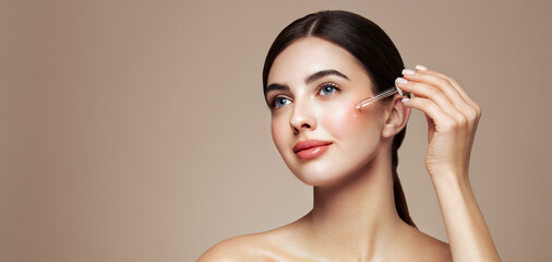 Young beautiful woman applying face serum with pipette. Cosmetic procedures for facial skin care