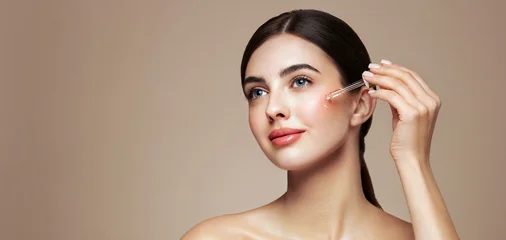 Young beautiful woman applying face serum with pipette. Cosmetic procedures for facial skin care © Oleg Gekman