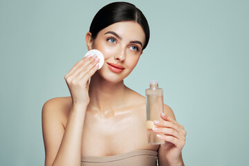 Young girl holds cotton pad while cleansing face with cosmetic milk. Skin care removal of makeup cleansing. Basic facial skin care