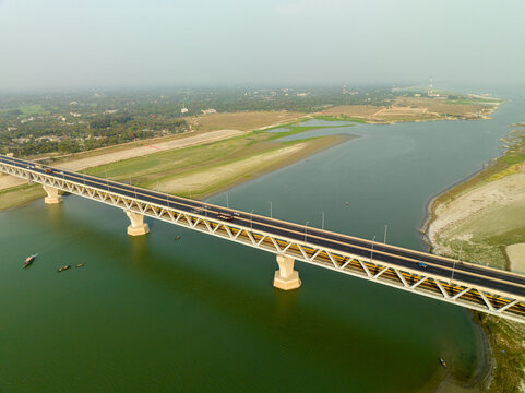 Aerial view of the Padma Multipurpose Bridge stretching across the shimmering river, connecting vibrant lands with a promise of progress, Mawa, Dhaka Division, Bangladesh.