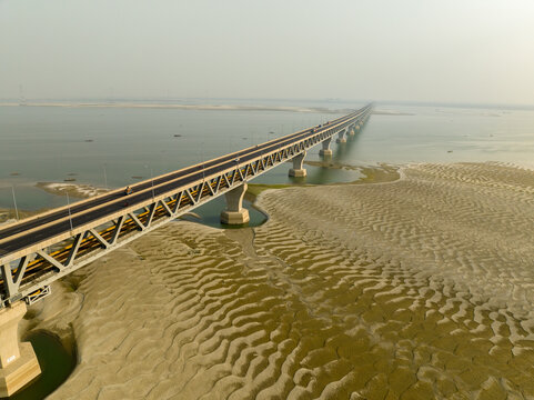 Aerial view of the Padma Multipurpose Bridge stretching across the wide, sandy riverbed under a pale sky, Mawa, Dhaka Division, Bangladesh.