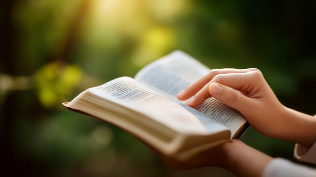 Female hands gently pointing to an open scripture passage, sunlight streaming across the pages, defocused forest greenery in background, Bible study, faith, devotion, prayer guidance, spiritual