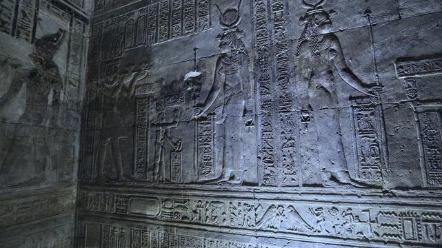 Dendera temple interior sanctuary with illuminated hieroglyphic walls and ritual reliefs in Egypt, ancient sacred chamber with dramatic lighting on carved sandstone surfaces.