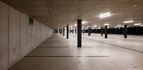Front view of a new light-colored public parking lot with black stripes and columns. Nobody inside