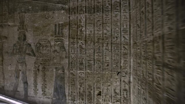 Dendera temple interior sanctuary with illuminated hieroglyphic walls and ritual reliefs in Egypt, ancient sacred chamber with dramatic lighting on carved sandstone surfaces.