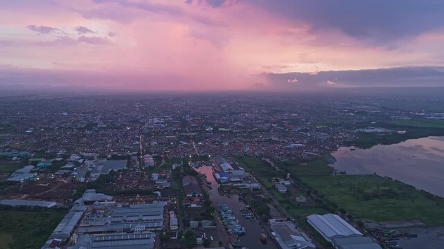 Aerial view of the coastal city of probolinggo in east java, indonesia. A stunning pink and purple sunset illuminates the cloudy sky