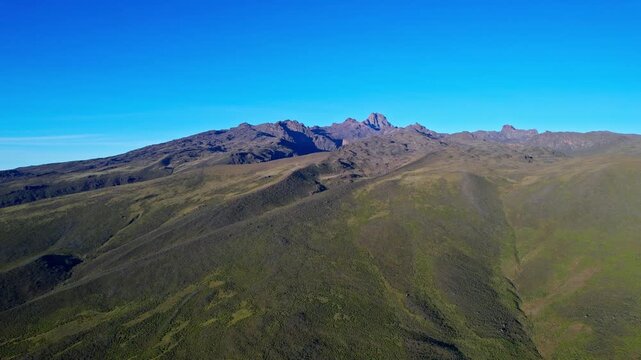 Aerial view of the rugged terrain of Mt Kenya, displaying stark contrasts between the dark, rocky peaks and the lush green slopes, Lake Ellis, Meru County, Kenya.