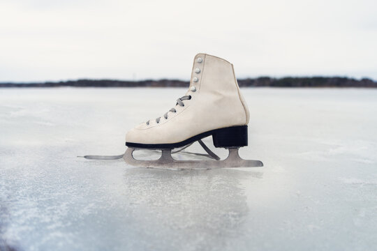 single ice skate standing upright on ice, symbolizing the concept of winter sports and outdoor recreational activities.