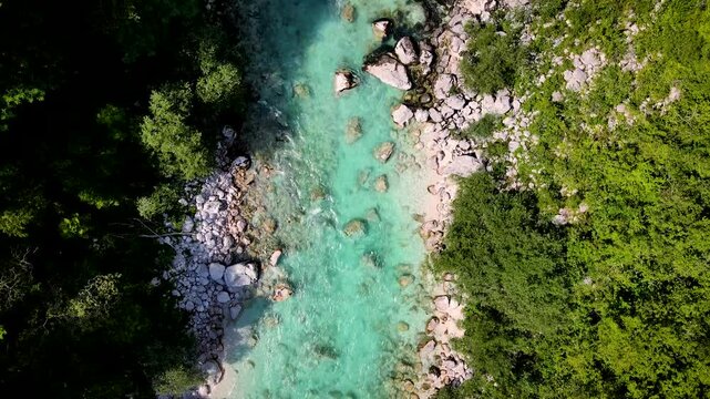 Aerial view of the turquoise Soca river flowing between forests and rocky banks, creating a stunning contrast of colors, Kobarid, Tolmin, Slovenia.