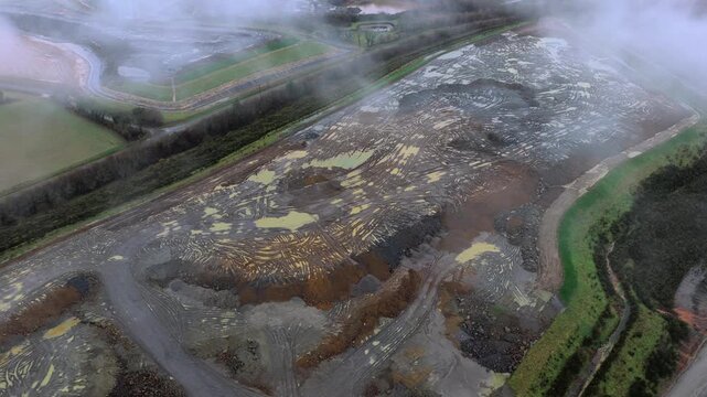 Aerial view of a landfill showing textures of mud and tyre tracks, with a cloudy sky, Glomel, Brittany, France.
