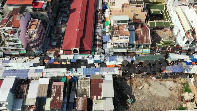 Drone shot of a vibrant market with colorful tarps and umbrellas covering stalls in Chau Doc, Vietnam, surrounded by dense urban buildings.
