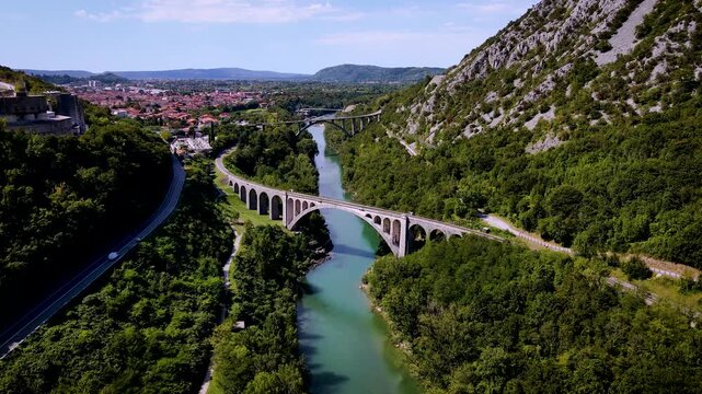 Aerial view of Solkan bridge over the turquoise river, surrounded by lush green trees and mountains, Solkan, Nova Gorica, Slovenia.