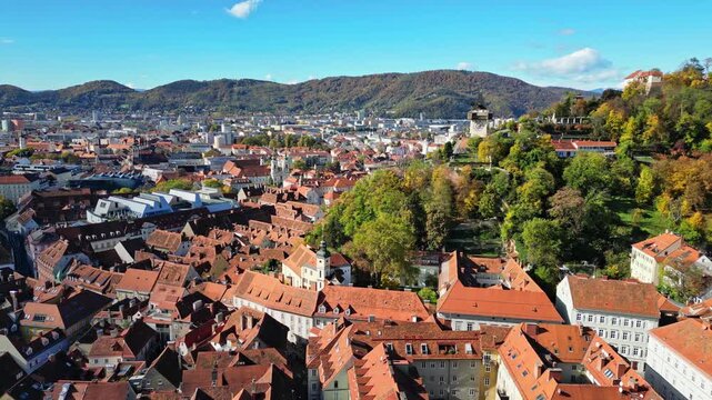 Aerial view of the old town, with red rooftops and the iconic Uhrturm clock tower standing sentinel over Graz, Styria, Austria.