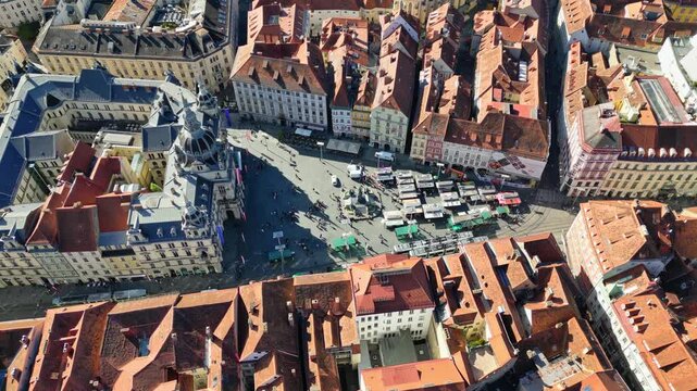 Aerial view of the Hauptplatz with its bustling market stalls, showing a vibrant scene nestled among buildings with terracotta roofs, Graz, Styria, Austria.