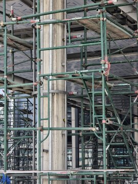 A construction site with scaffolding and a tall structure. The scaffolding is green and has red and white markings