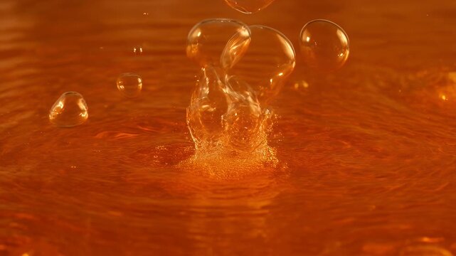 A translucent liquid splash forms a crown-like shape in amber liquid, with bubbles
