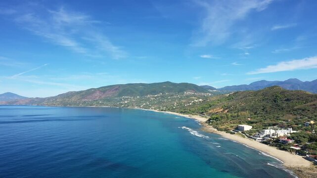 Scenic aerial view of the clear blue sea and lush green hills along the coastline of Palinuro, Italy, on a sunny day.