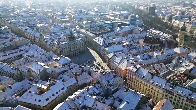 Aerial view of Hauptplatz square where snow-covered roofs contrast with clear streets, creating a striking winter panorama, Graz, Styria, Austria.