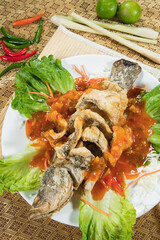 A whole fish is deep fried until crisp and served over a pool of bright chili sauce. Lettuce, lemongrass and lime garnish the plate for a bold, tropical presentation.
