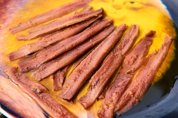 Anchovy fillets soaking in olive oil on plate