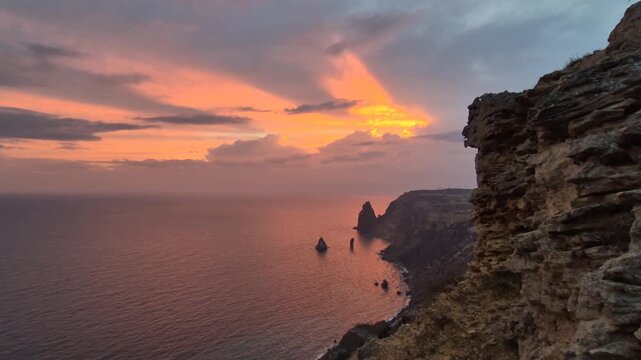 Sunset ocean cliff dramatic seascape view over rocky coastline and sea stacks at dusk with brilliant orange sky
