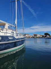 Fototapeta premium Grimaud,France - Febrary 18,2026:Blue yaht moored on calm water, where it reflected, at the Grimaud port