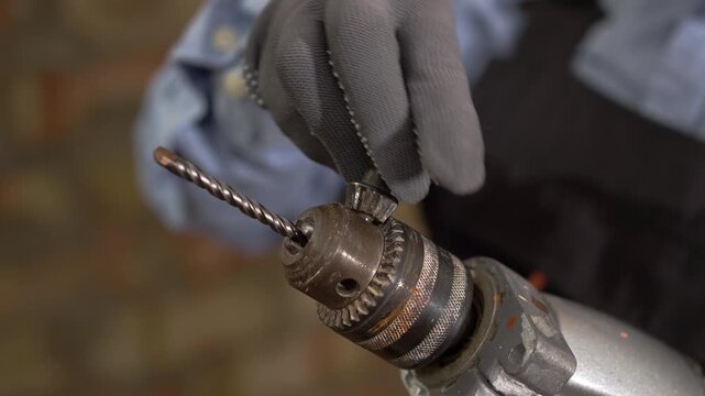 Close up of installing a metal drill bit into a chuck of electric power tool for renovation works