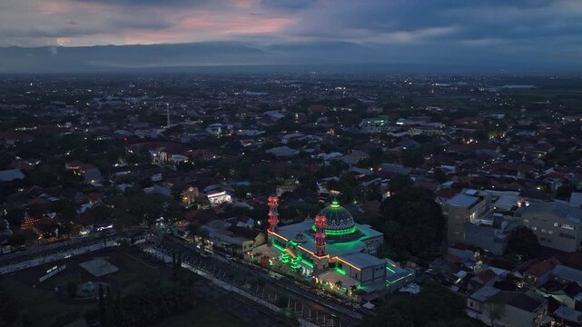 Striking aerial perspective of the city of probolinggo in east java, indonesia, featuring a grand mosque illuminated by vibrant green lights at dusk