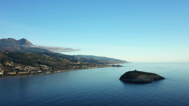 Scenic aerial view of Isola di Cirella and the coastline with mountains in the background, Calabria, Italy. Calm blue sea and coastal landscape under clear sky.