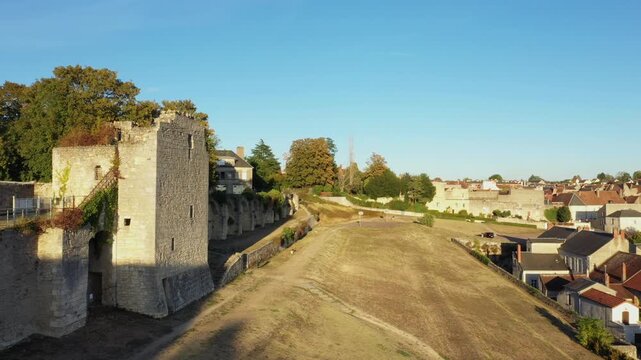 Historic stone fortifications and old town buildings in La Charite sur Loire, France, captured under clear blue sky. Peaceful rural landscape with medieval architecture.