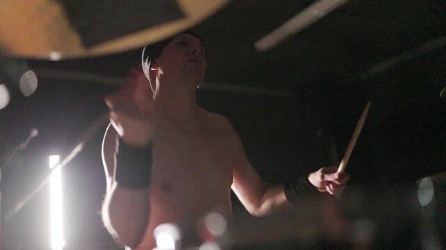Shirtless male drummer playing drums energetically