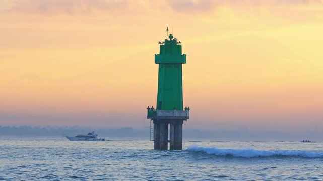 Ocean Wave Splash Framing a Green Navigation Beacon