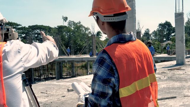 Engineer and surveyor worker working with theodolite transit equipment at outdoors construction site. 4K
