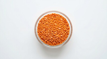 Red lentils in a clear glass bowl on white background