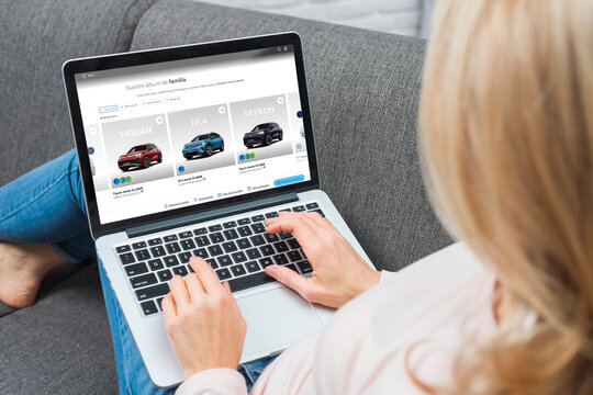 Woman shopping cars online using laptop on couch