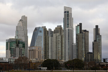 Obraz premium Modern skyscrapers shape the Puerto Madero skyline, featuring Alvear Tower and Alvear Icon Hotel, under an overcast sky.